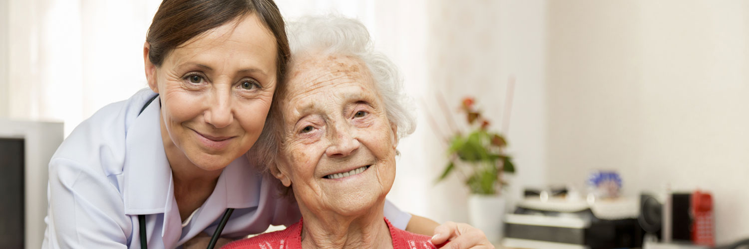 caregiver with her arms around elderly woman